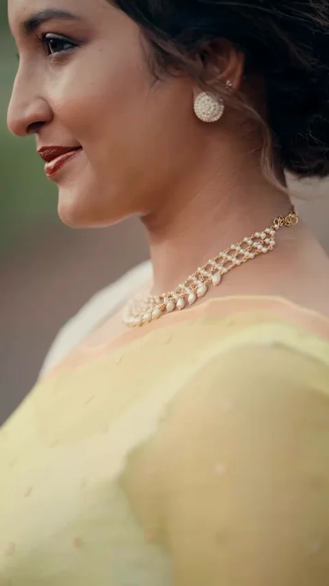 A pearl necklace and earrings styled with a yellow saree outdoors.
