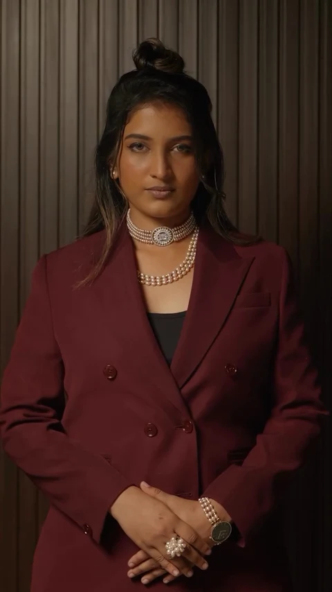 A pearl choker and pearl accessories styled with a burgundy suit.
