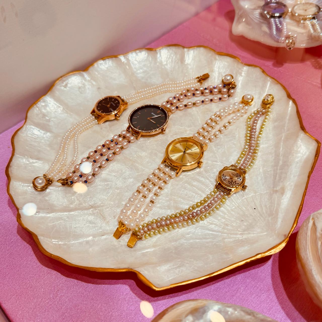 Pearl watches displayed on a mother-of-pearl shell dish